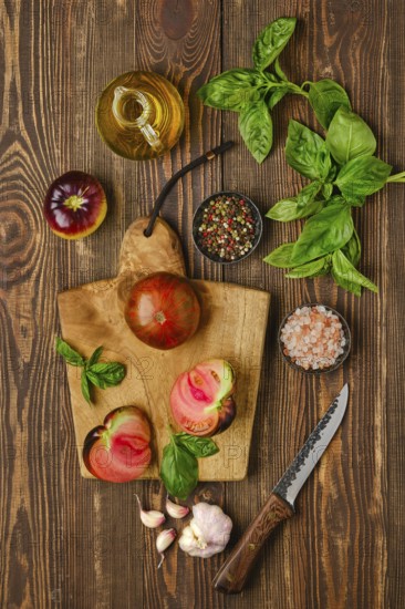 Fresh meaty tomato on wooden cutting board with basil and spice