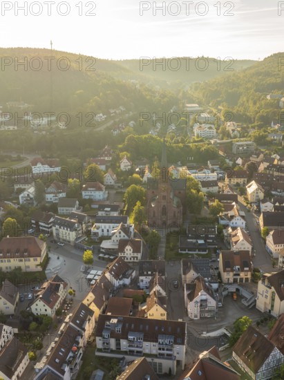 Idyllic close-up of a village with church, surrounded by hills and trees in the light of the sunset, Nagold, Black Forest, Germany