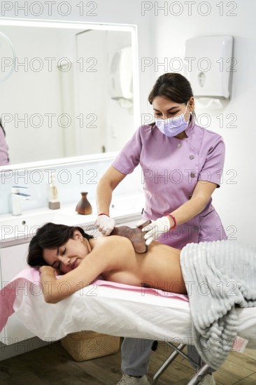 A qualified therapist provides a soothing massage to a client at a beauty salon specialized in aesthetic medicine. The tranquil environment promotes relaxation and wellness