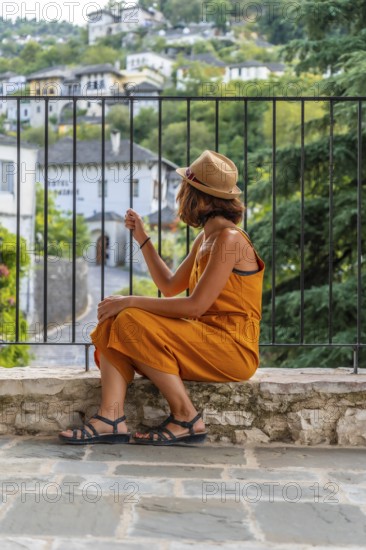 Portrait of a sitting tourist woman looking from a viewpoint at the city of Gjirokaster or Gjirokastra. Albanian