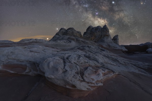 A breathtaking view of Utah's desert landscape under a star-studded Milky Way. No people in this serene nighttime scene composed of rocky formations and a clear view of celestial wonders