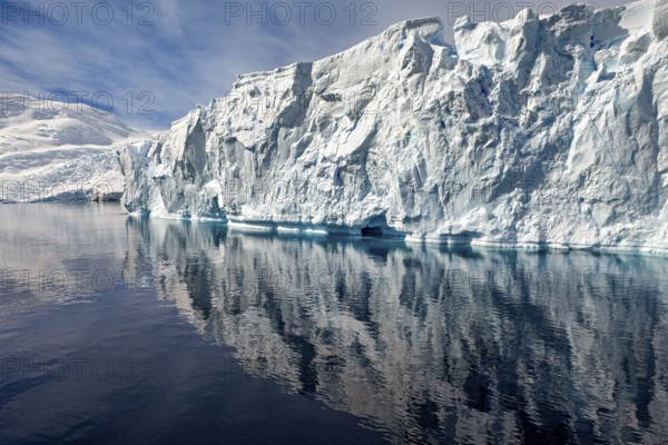 Fascinating iceberg formation with clear reflection in calm water under a blue sky, icebergs in the landscape of the Southern Ocean in Antarctica