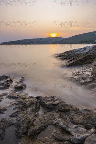 Sunset over crystal clear water on the beach of Ustrine Bay on the island of Cres, long exposure, Croatia