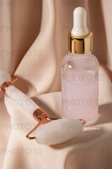 A sleek jade roller and a glass dropper bottle containing pink serum sit on elegant fabric These beauty tools enhance daily skincare regimes, promoting relaxation and rejuvenation