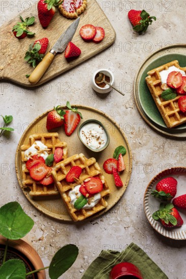 Rustic homemade waffles topped with fresh strawberries, yoghurt, and mint. Served on ceramic plates, creating a sweet and romantic dessert setting