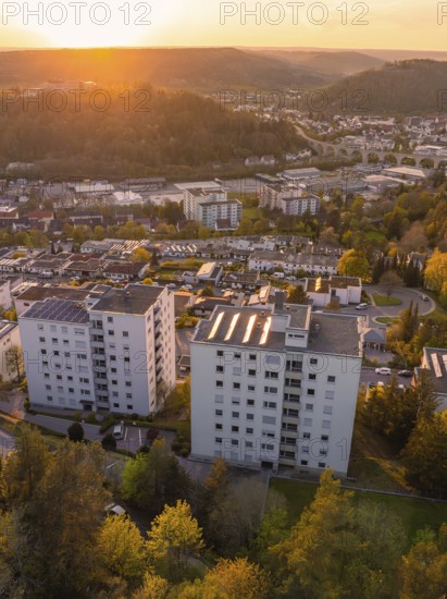 Tall buildings in a cityscape at sunset, surrounded by nature and hills, Nagold, district of Calw, Germany