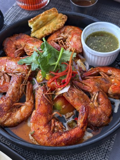A flavorful dish of seasoned fried shrimp served with a spicy dipping sauce in a Thai cafe setting