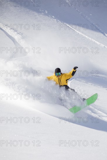 A snowboarder in a vibrant yellow jacket expertly carves through fresh powder on a snowy mountain slope, creating a dynamic spray of snow and an exciting action scene