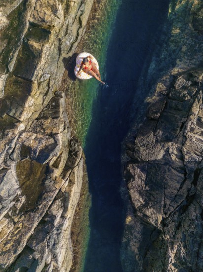 Top view of an unrecognizable woman floating on an inflatable in the clear, waters of a natural pool on the rugged coastlines of Tindaya Beach, Fuerteventura. Capturing the tranquility and untouched beauty of this hidden gem in the Canary Islands
