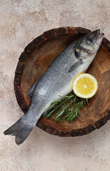 Fresh, raw sea bass fish, in a wooden plate, top view, no people.