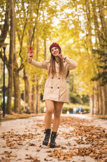 Portrait of a beautiful woman in autumn next to a forest in nature making a video call