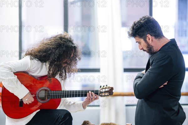 Man listening to popular guitarist playing bass guitar in studio