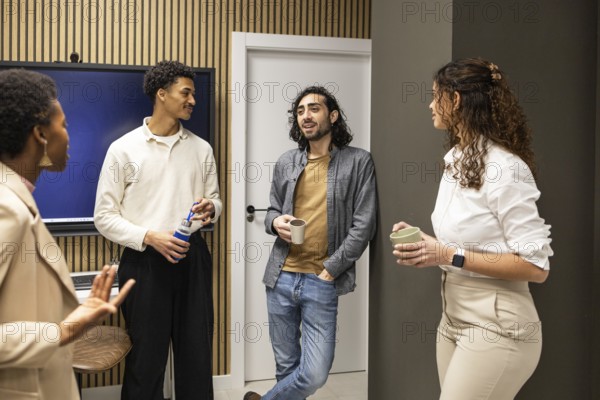 Group of colleagues in a contemporary office setting, engaged in a casual conversation during a coffee break. Modern decor enhances the relaxed atmosphere