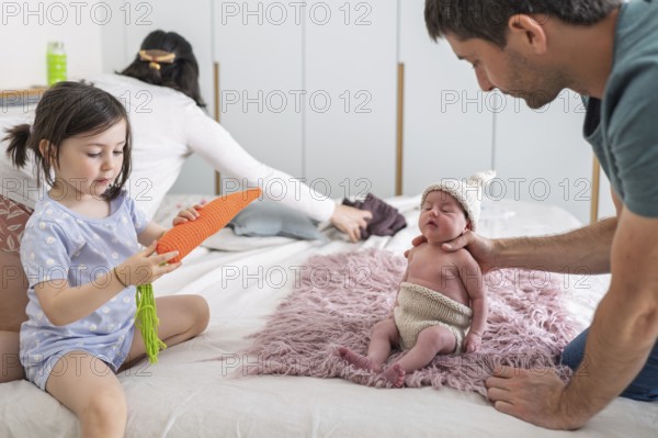 A young family shares tender moments with their newborn baby and big sister. The joyful scene captures the essence of family love, connection, and the warmth of a shared home