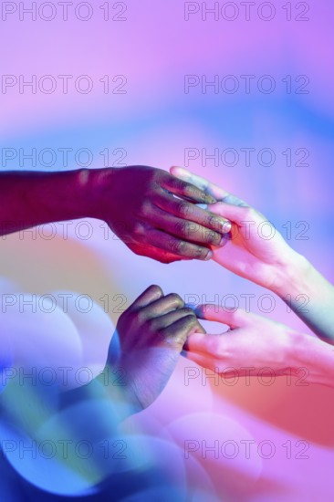 Multiethnic hands gently holding each other with vibrant colored lighting in the background, symbolizing unity and diversity in a harmonious, artistic setting