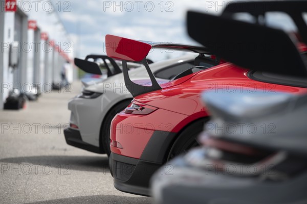 A lineup of high-performance sport cars with prominent rear wings, showcasing advanced aerodynamics and sporty design, parked along a racetrack