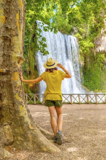 A tourist woman with a hat looking at La Caprichosa waterfall in the Monasterio de Piedra Natural Park, Aragon, Spain