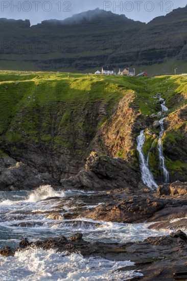 Houses against a mountain backdrop, rocky coast, sea, surf, Vidareidi, Vidoy Island, Viðareiði, Viðoy Island, Faroe Islands, Denmark