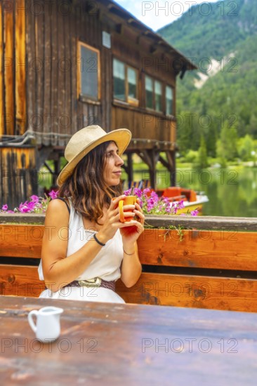 Woman relaxing at lake dobbiaco with a mug, enjoying the mountain landscape in the dolomites