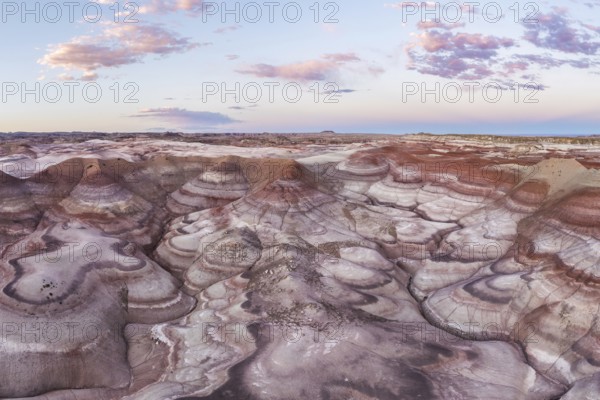 Stunning aerial shot capturing the unique patterns and vibrant earth tones of bentonite landscapes in Utah, under a soft sunset sky