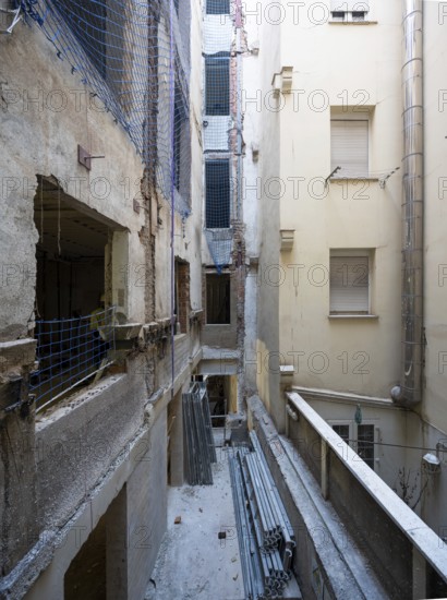 A detailed view of an urban renovation project, with exposed walls, construction materials, and safety netting, illustrating the ongoing progress and structural work