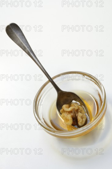 Walnut with spoon in blossom honey, honey and walnut