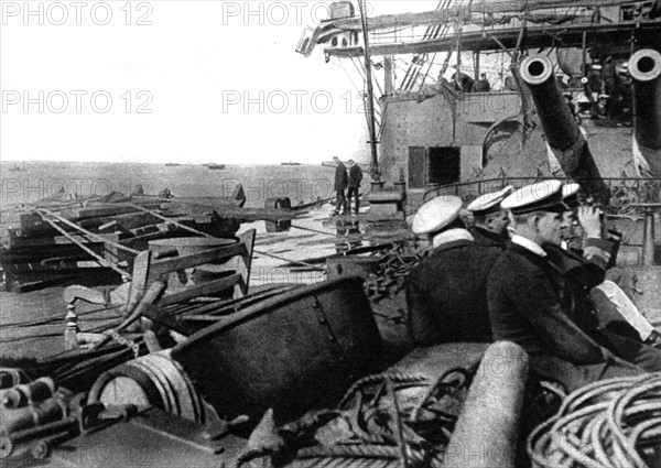 Première Guerre Mondiale. A l'entrée des Dardanelles, un cuirassé anglais avance, paré pour le combat, dans la ligne des chalutiers relève-mines devant Seddul-Bahr