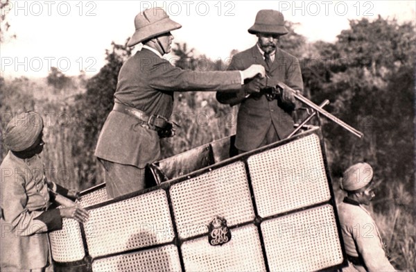 Le souverain George V d'Angleterre, sur son éléphant de chasse, fait charger son fusil (Népal, 1912).