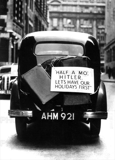 London. Automobile with a sign that reads: "Half a moment, Hitler, let's save our holidays first"