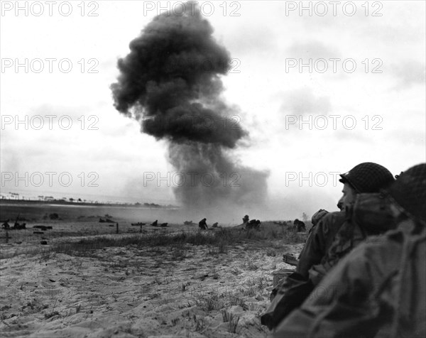 Débarquement en Normandie. Un bombardement d'obus ennemis sur la plage tandis que les troupes américaines avancent