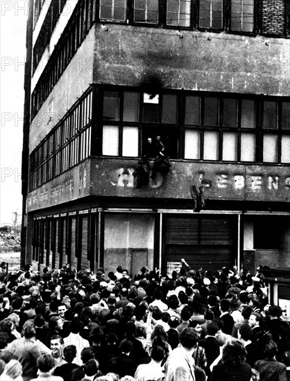 East Berlin: Policemen throwing their uniforms out of windows from a governmental building surrounded by demonstrators