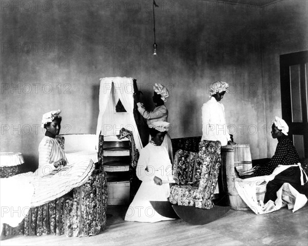 Photo de J.B. Johnston. Etudiantes noires pendant un cours de décoration et de couture