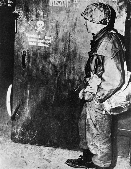 American soldier before a gas chamber door at a Nazi Concentration Camp