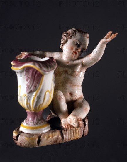 Candleholder decorated with a cherubin figure.