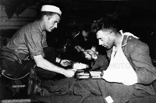 Un marin américain aide un prisonnier allemand (juin 1944, après le Jour J)