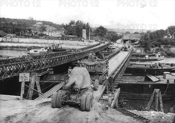 Un canon U.S. de 155 mm traverse un pont "Bailey" qui enjambe la Seine.
(Eté 1944)