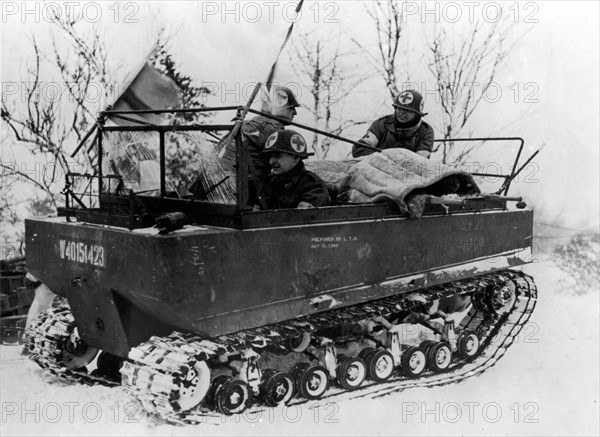 Des hommes du corps médical américain évacuent un blessé en ambulance.
(1er février 1945)