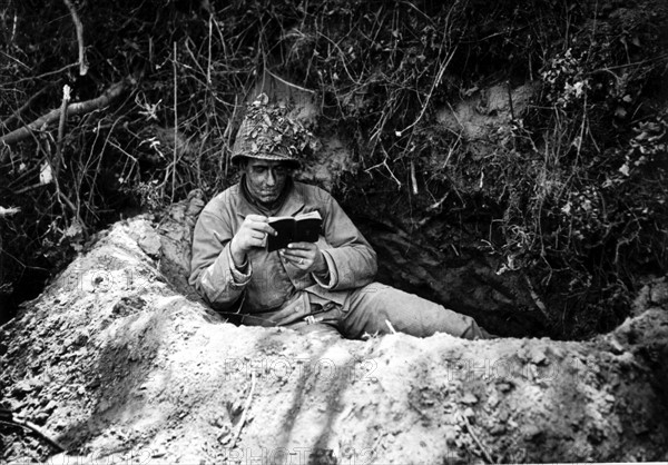 Soldat américain lisant un recueil de prières, dans la région de Saint-Lô.
(Juillet 1944)