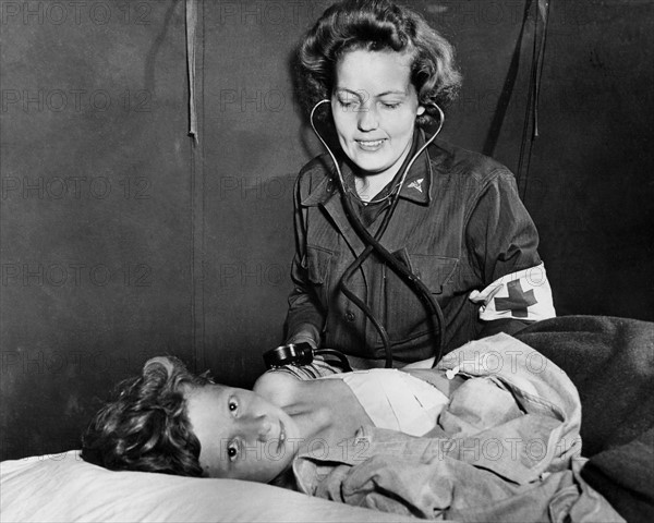 Infirmière de l'U.S. Army soignant un enfant français blessé en Normandie.
 (Eté 1944)