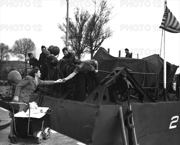 Un marin américain tend un fruit à une jeune femme en France, 2-3 avril 1945