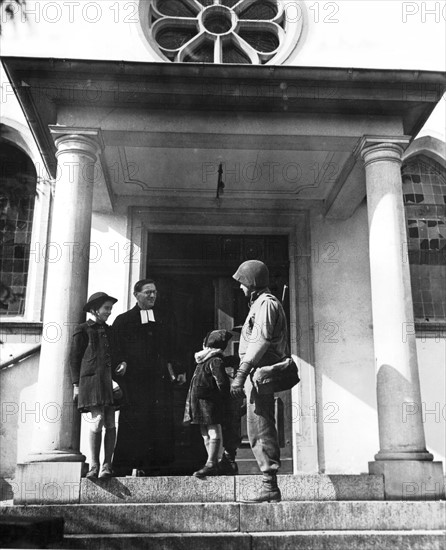 Un soldat américain en conversation avec un pasteur alsacien à Woerth, mars 1945.