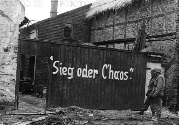 American engineers read Nazi sign in Vettweiss, March 1945