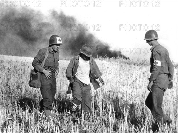 Medics assist an injured American soldier on the Sicilian front, July 22, 1943