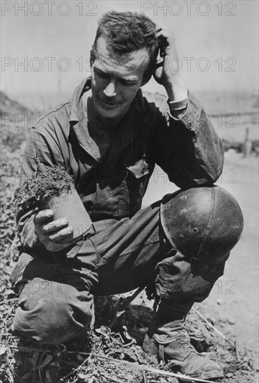 Soldat américain examinant une mine allemande en Normandie
(Juillet 1944)