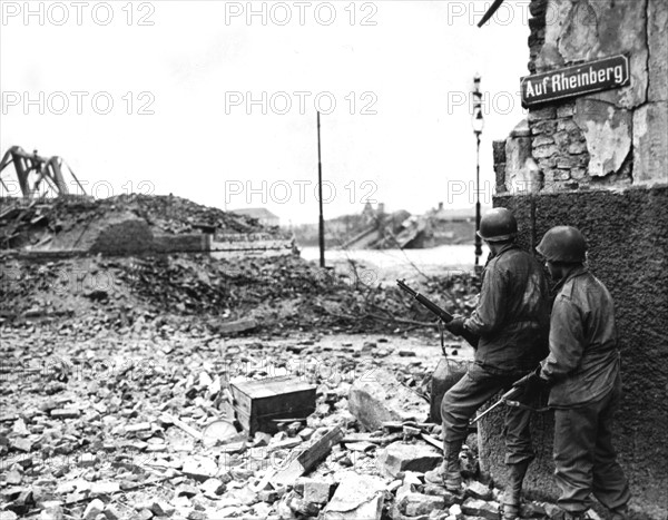 American infantrymen peer wearily around a street corner in Cologne (Germany) March 6, 1945.