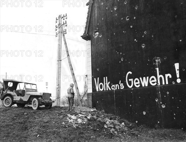 Soldat américain découvrant un slogan qui enjoigne les Allemands à prendre les armes. (Décembre 1944)