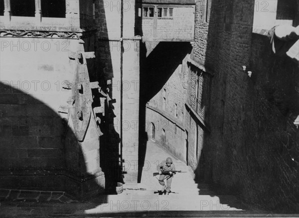 Un soldat d'infanterie américain monte les marches de l'abbaye du Mont Saint-Michel. (Août 1944)