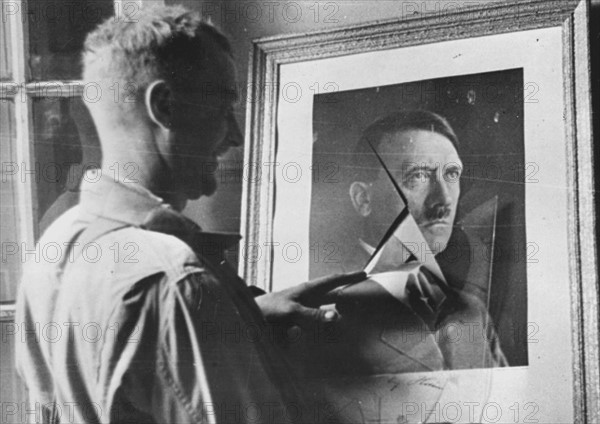 A GI looking at Hitler's portrait