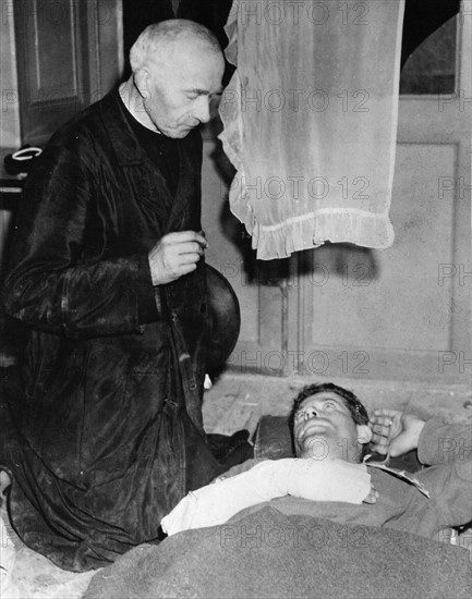 A French priester receiving the confession of an injured American soldier (1944)