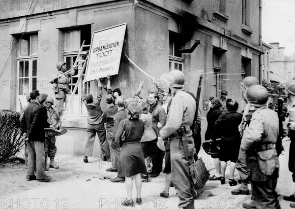 La population cherbourgeoise détruit l'insigne du bureau de l'Organisation Todt juste après la libération